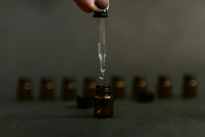 Compte-goutte versant une goutte de liquide dans un flacon en verre