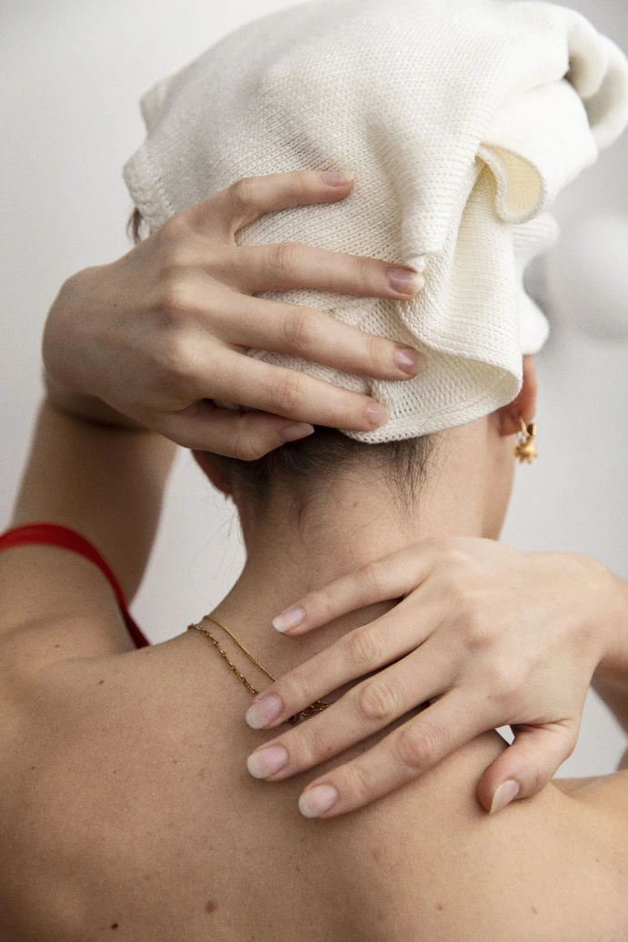 Femme de dos, portant un essuie dans ses cheveux